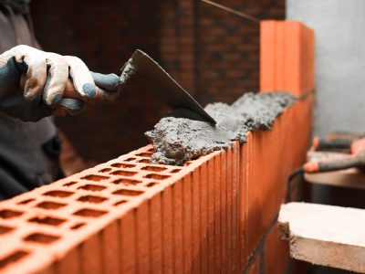 Bricklayer puts bricks to make a wall